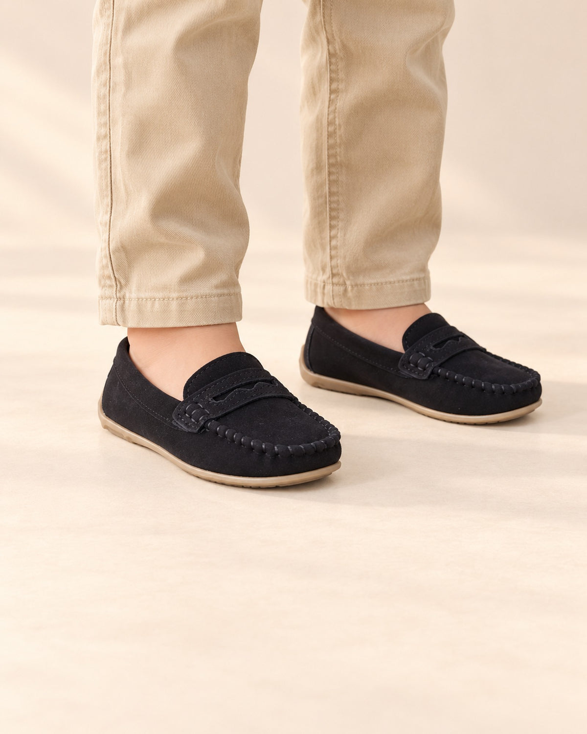 Close-up of a boy's feet in black suede-look moccasin loafers with khaki chinos – Black