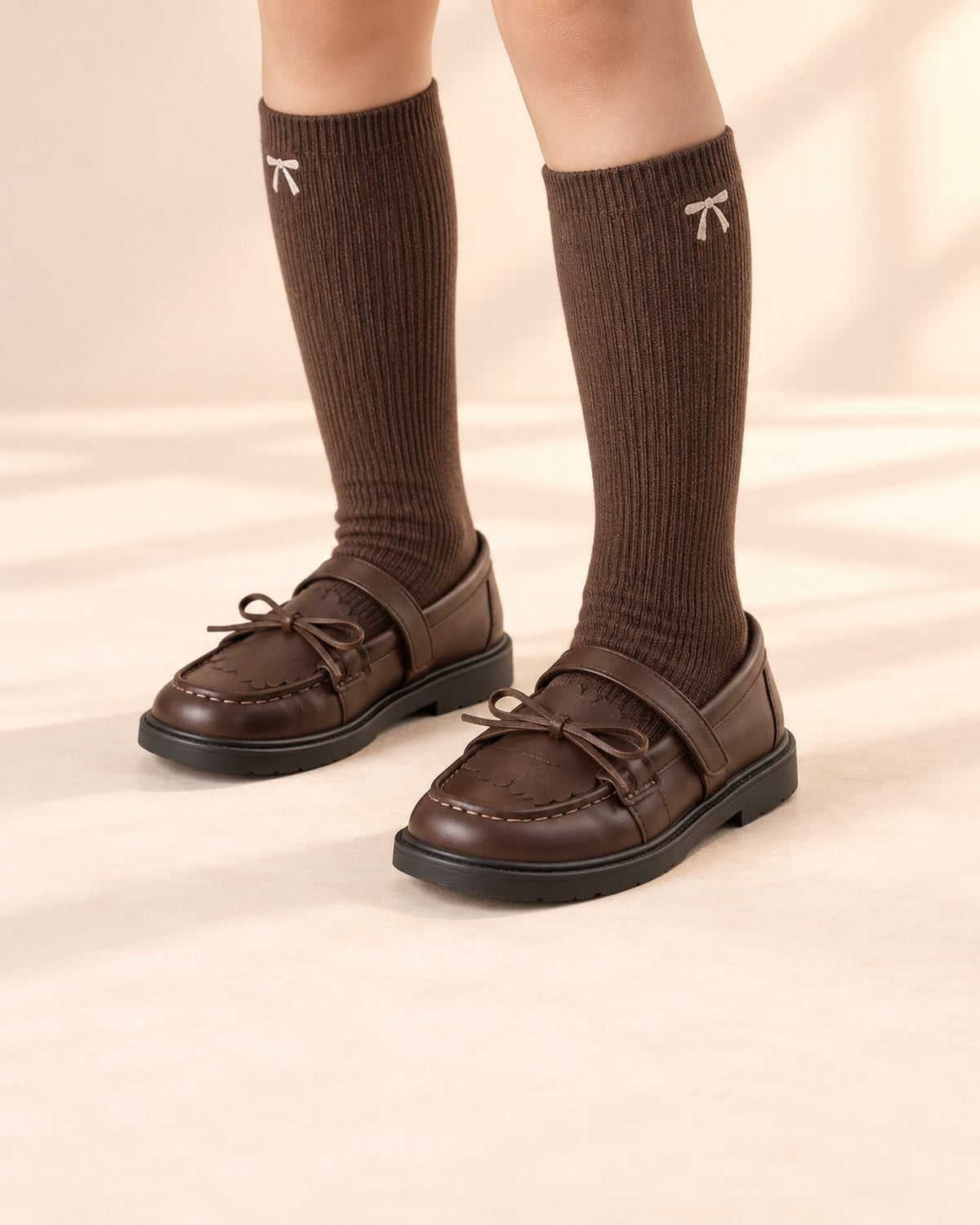 Close-up of a girl's feet in brown bow loafers with chocolate ribbed knee socks – Brown