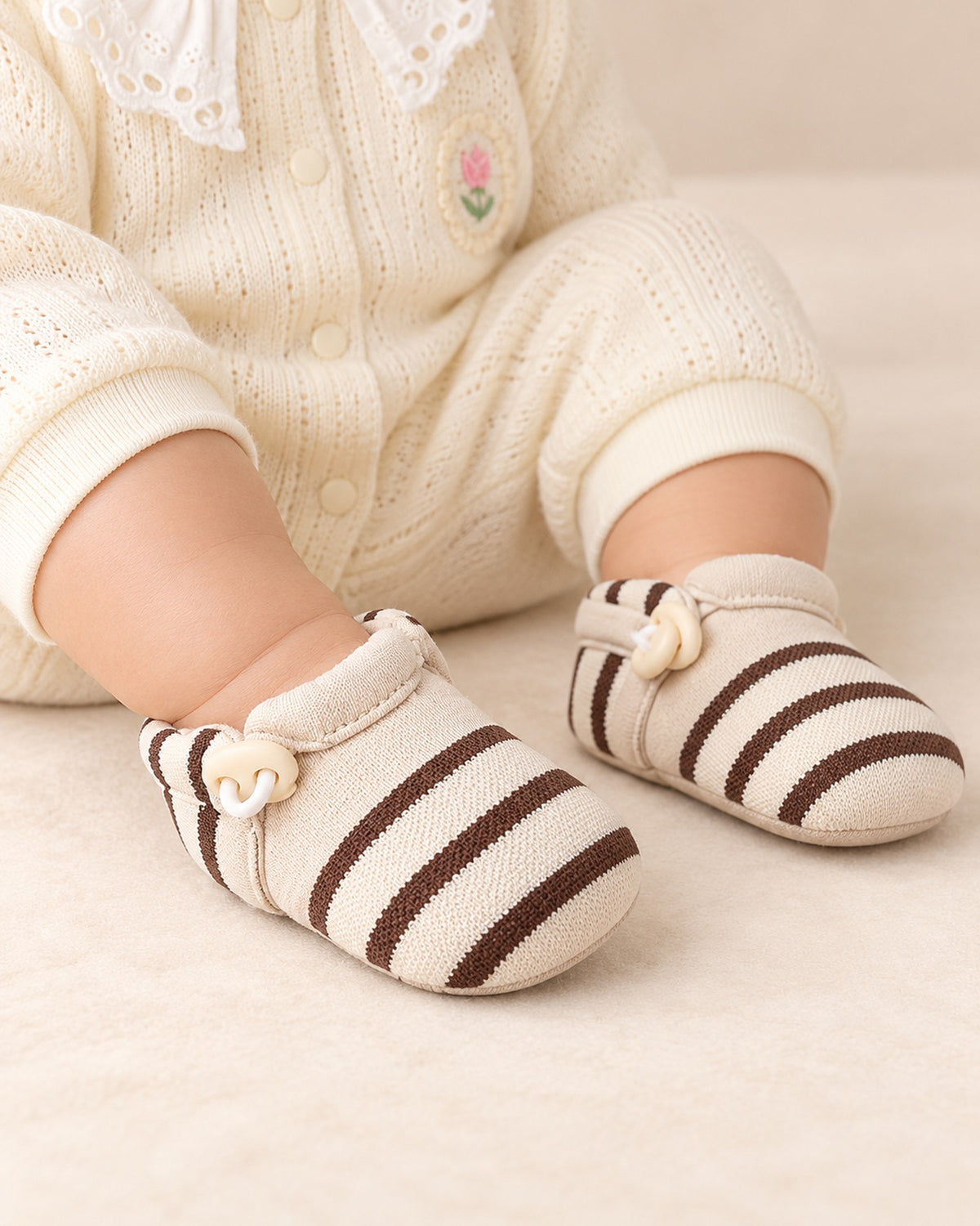 Close-up of a baby's feet in cream and brown striped sock shoes – Brown Stripe