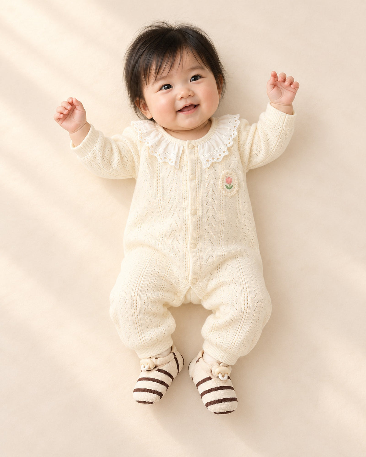 Front view of a baby in a cream lace collar knit romper and striped sock shoes, full length – Brown Stripe