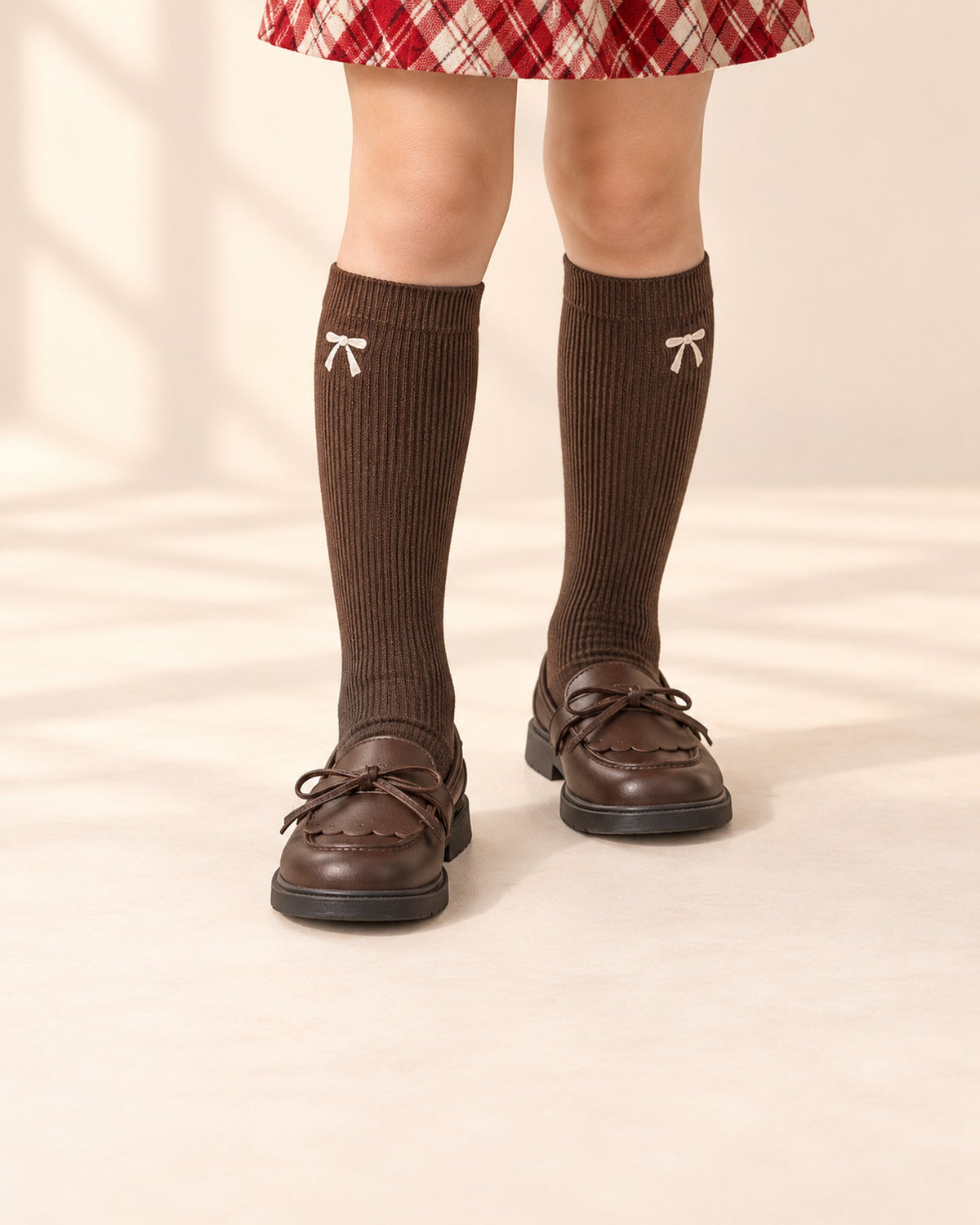 Close-up of a girl's legs from knee to floor in chocolate ribbed knee socks and brown bow loafers – Chocolate