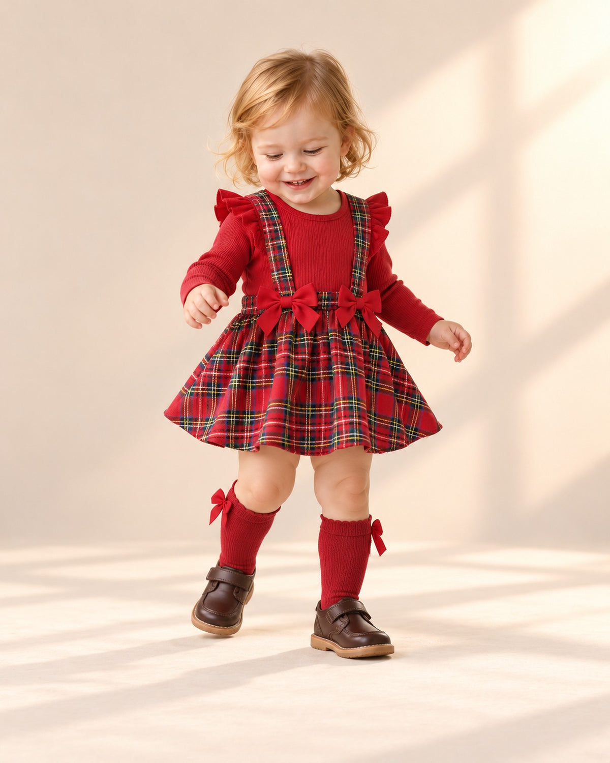 Toddler girl playing with a present in her tartan dress and red bow socks – Red