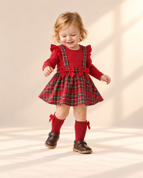 Toddler girl playing with a present in her tartan dress and red bow socks – Red
