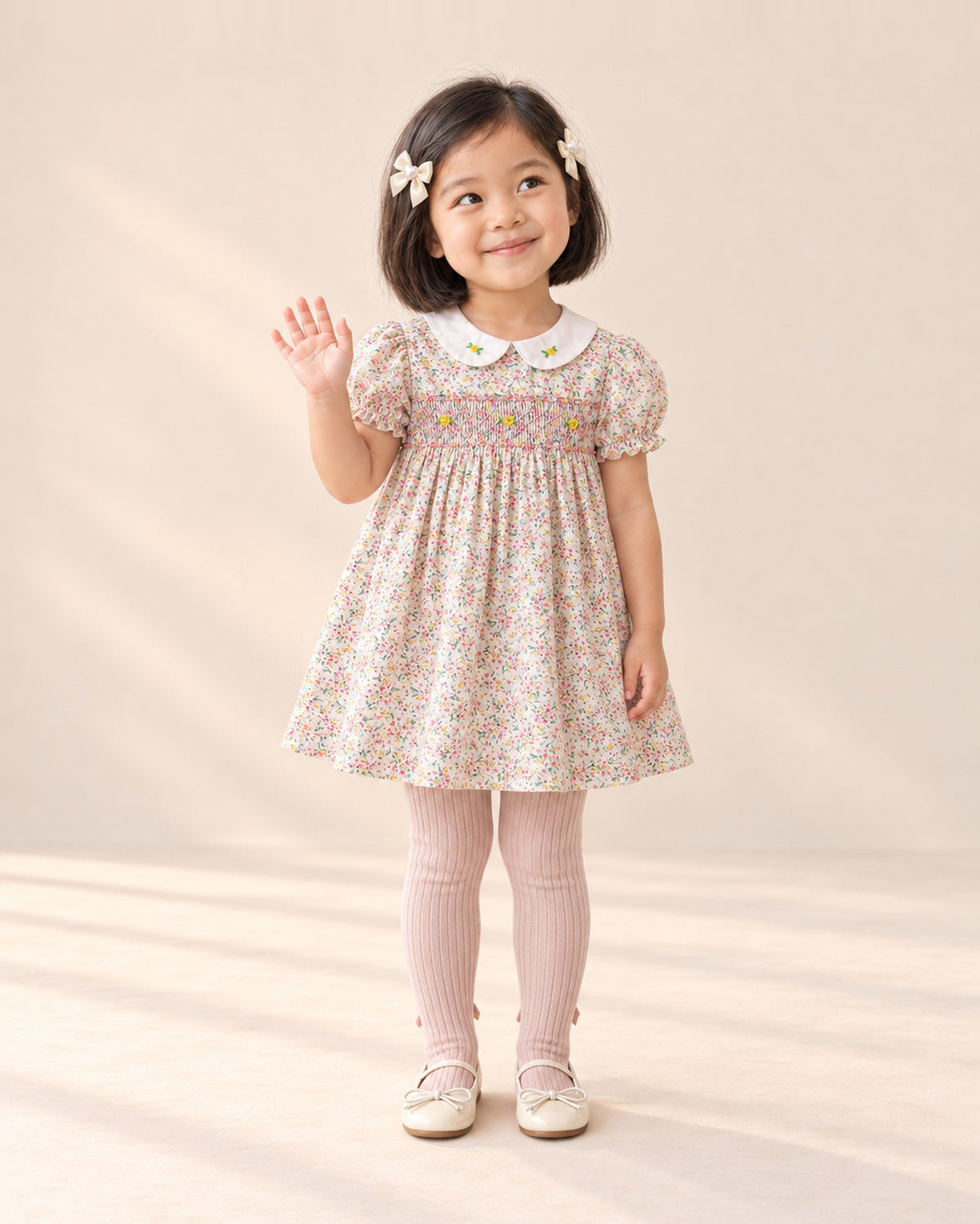 Front view of a girl in a pink smocked floral dress, blush bow tights and cream bow flats, full length – Blush Pink