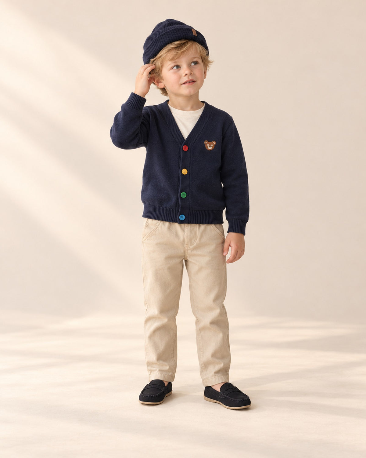 Front view of a boy in a navy beanie, navy bear cardigan, cream tee, khaki chinos and black loafers, full length – Navy