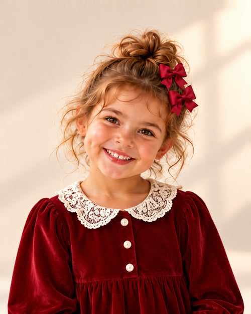 Close-up of a girl's head and shoulders with red grosgrain bow clips on her pigtails – Red