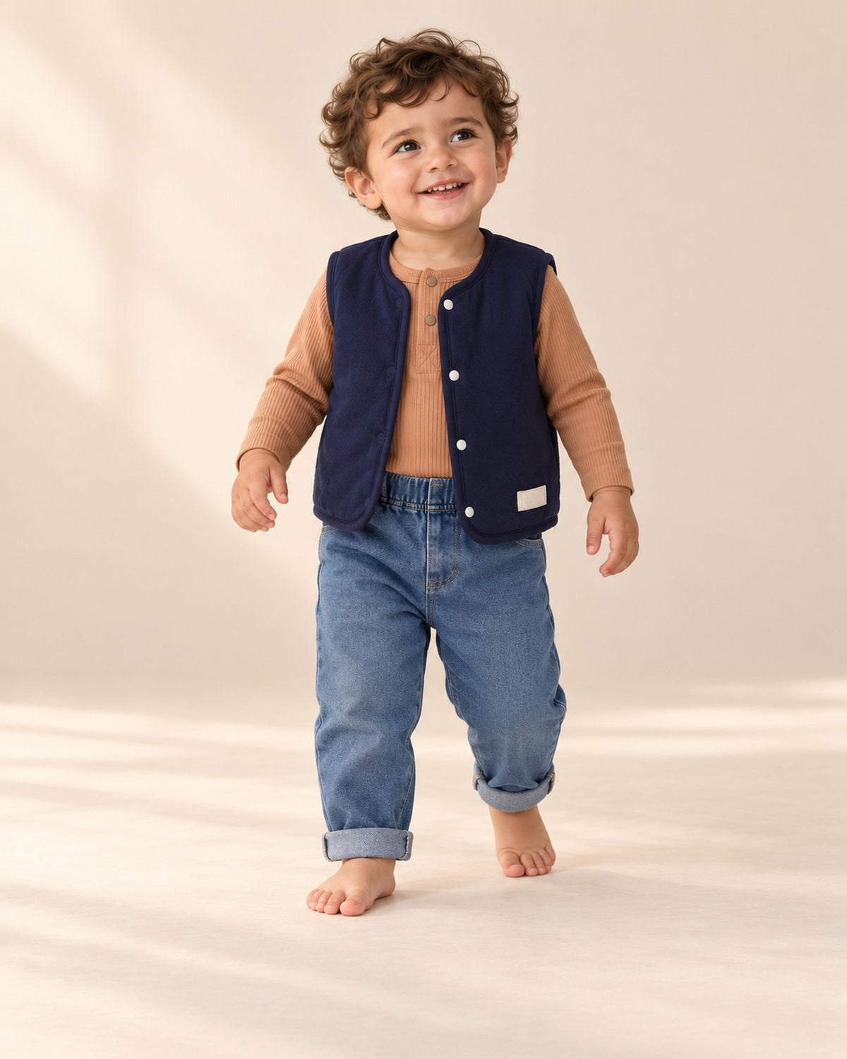 Little boy in the navy Hamish vest and jeans, playing on the studio floor in the full outfit – Navy