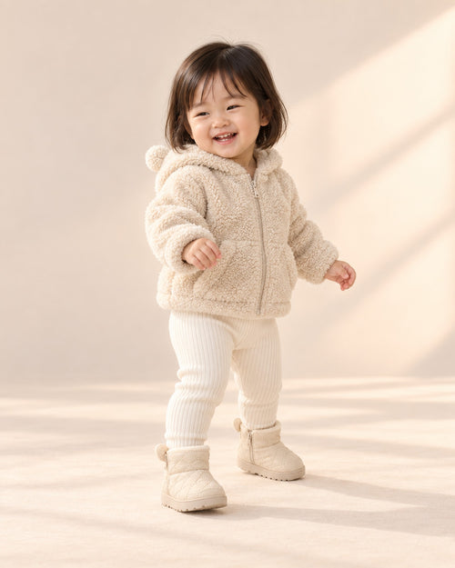 Toddler in the cream bear ear booties and sherpa jacket, taking a few steps across the studio – Cream